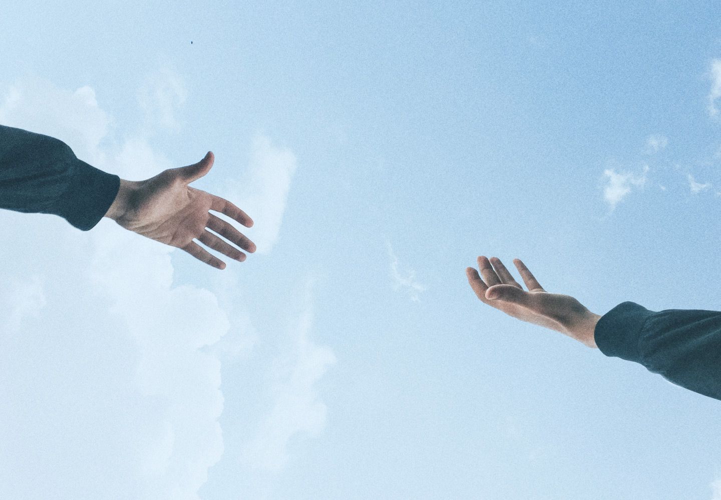 Manos extendidas con el cielo de fondo